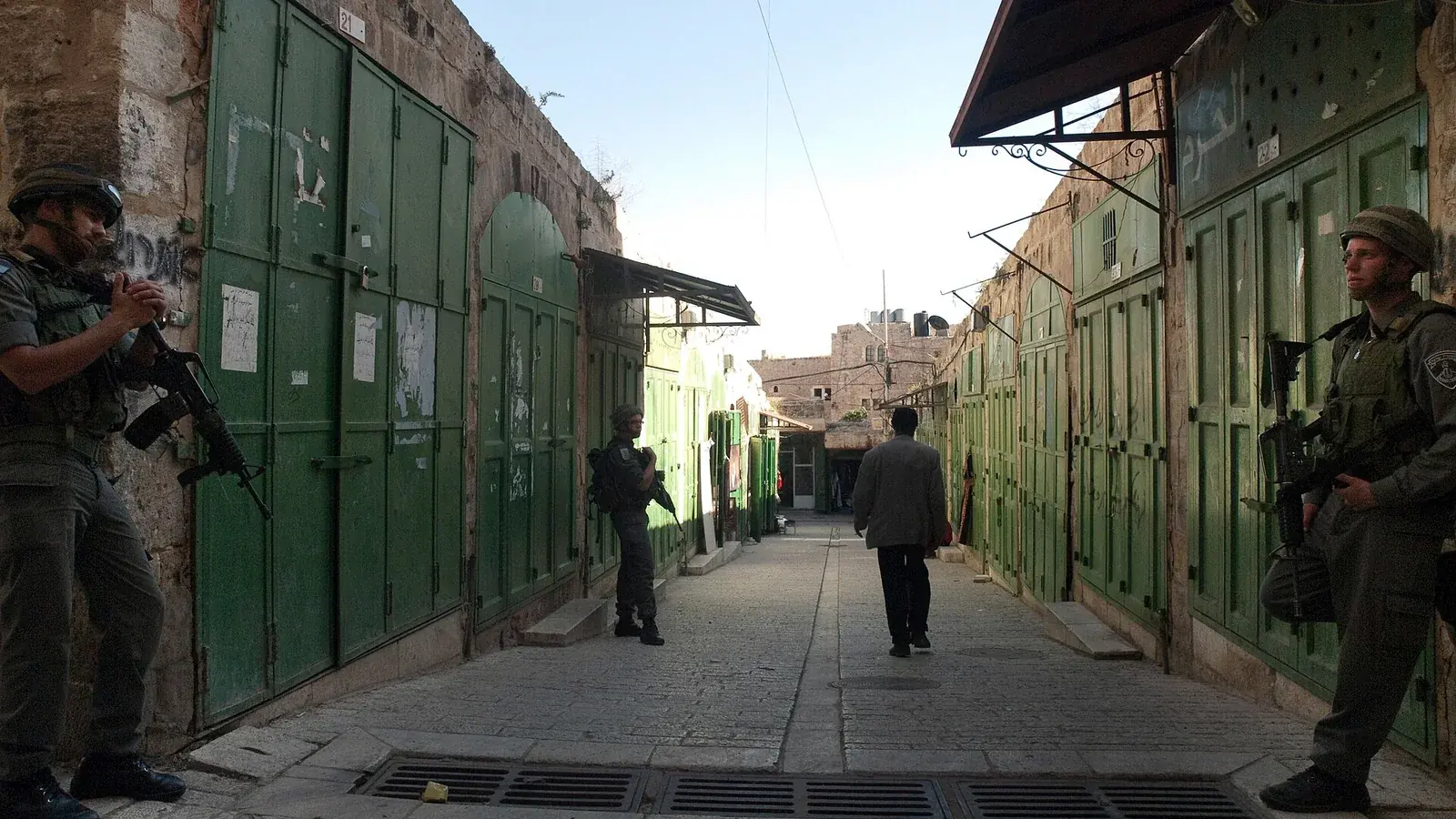جنود إسرائيليون يقفون أمام متاجر فلسطينية مغلقة في البلدة القديمة بالخليل